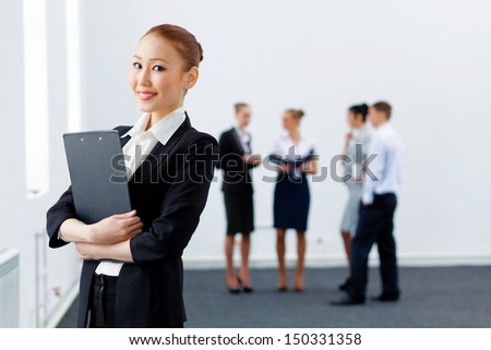 Asian young business woman holding folder with colleagues at background