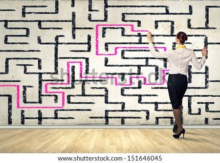 Back view image of young businesswoman trying to find way in labyrinth
