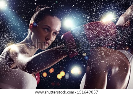 Two young pretty women boxing standing against flashes background