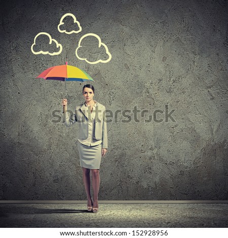 Young business woman in suit standing and holding an umbrella