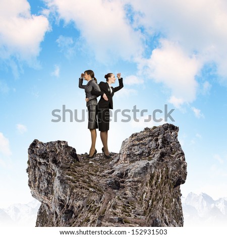 Image of two businesswomen looking into distance standing back to back