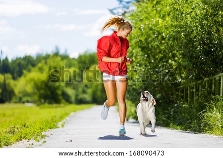 Young attractive sport girl running with dog in park