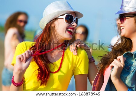 Image of two attractive young women in bright clothes having fun outdoors