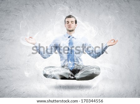 Young businessman sitting in lotus pose and meditating