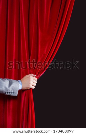 Close up of hand opening red curtain. Place for text