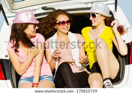 Three young pretty lady sitting in car boot