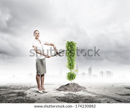 Young attractive businesswoman cutting plant in shape of exclamation mark