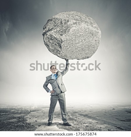 Powerful businessman holding huge stone above head