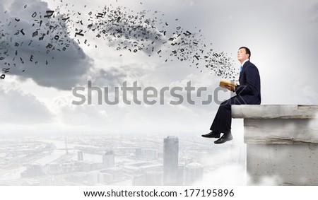 Businessman with book sitting on top of building