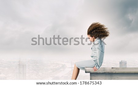Young businesswoman with waving hair sitting on top of building