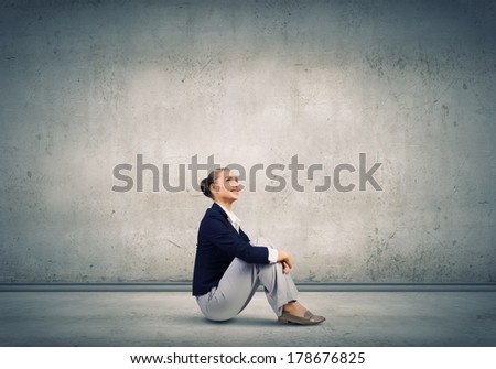 Young attractive lady sitting on floor of empty room