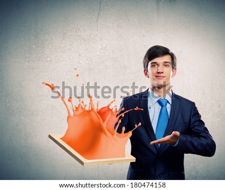 Handsome businessman holding frame with colorful splashes