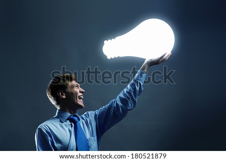 Businessman holding huge electrical bulb in hand