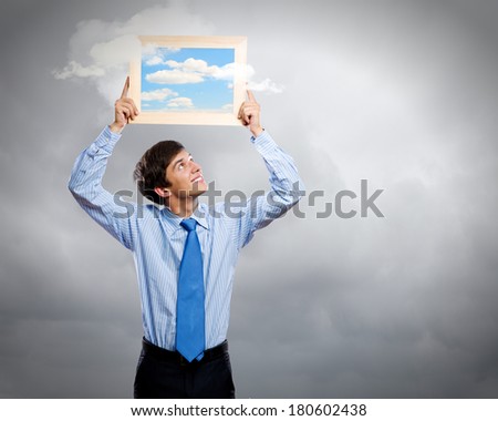 Handsome young man holding frame with pictures