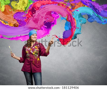 Young woman painter coloring wall with brush