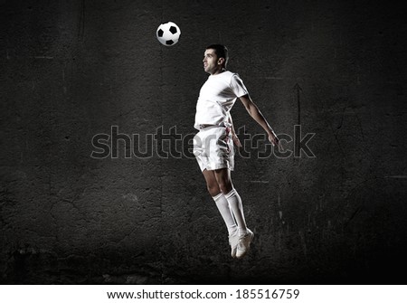 Football player kicking ball against dark background