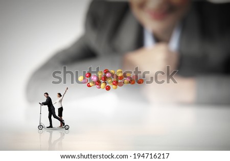 Businessman and businesswoman riding scooter with balloons in hand