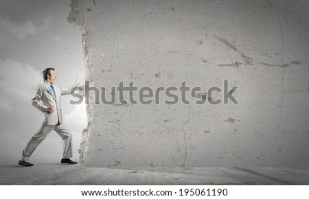Businessman breaking stone wall with karate punch