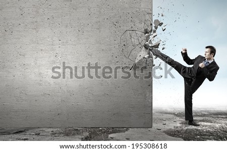 Businessman breaking stone wall with karate kick