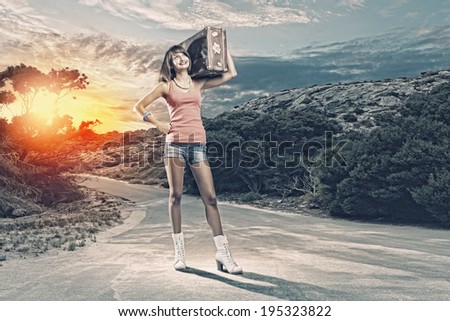 Young pretty woman tourist with suitcase walking on road