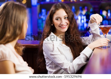 Two young pretty women at bar and drinking cocktails