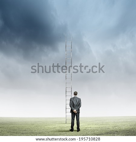 Rear view of businessman standing near ladder going high in sky