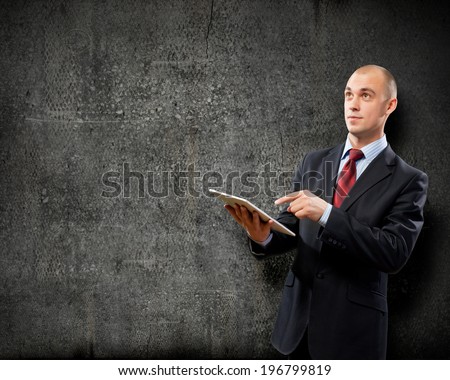 Young businessman against grey background using tablet pc