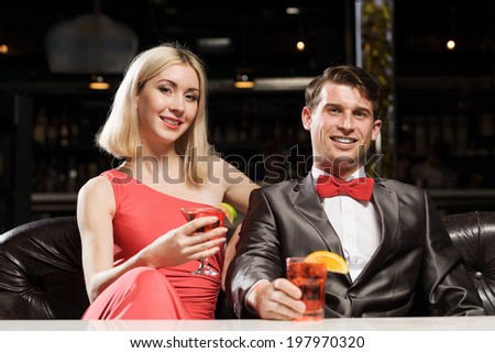 Young handsome man in restaurant accompanied by elegant lady