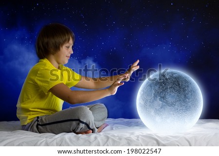 Cute boy sitting in bed with moon planet