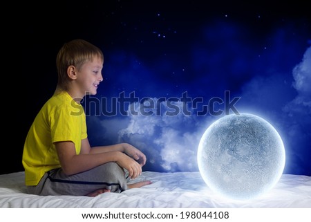 Cute boy sitting in bed with moon planet