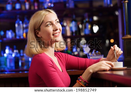 Young pretty lady sitting at bar with cup of coffee