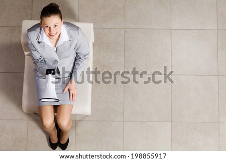 Top view of businesswoman sitting on chair with megaphone in hand