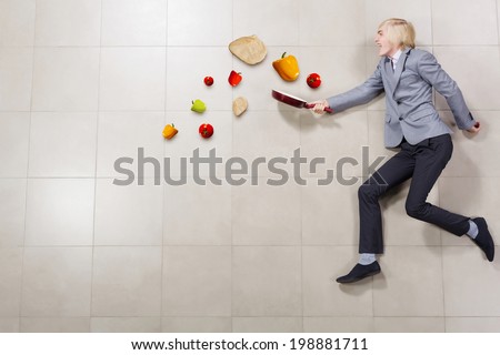 Funny image of young running businessman with pan in hand
