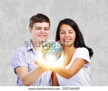 Young happy couple holding earth planet in palms. Elements of this image are furnished by NASA