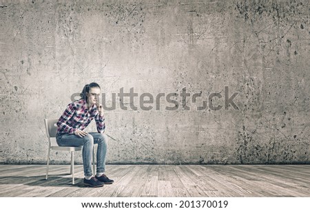 Young woman sitting on chair in empty room
