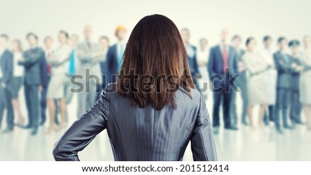 Powerful businesswoman standing with back with business team at background