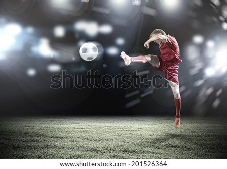 Young football player on stadium kicking ball