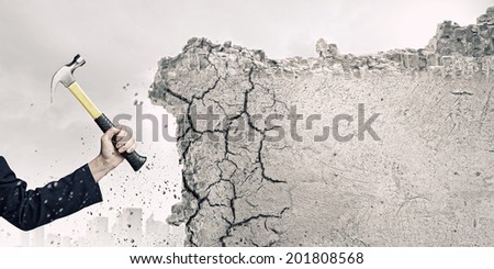 Close up of female hand crashing wall with hammer