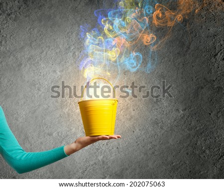 Close up of female hand holding bucket with colorful fumes