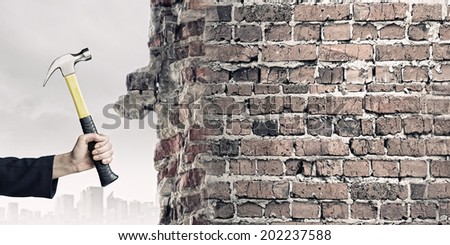 Close up of female hand crashing wall with hammer