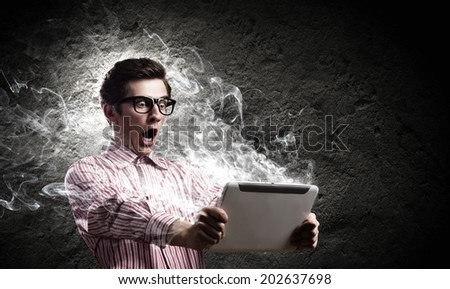 Young man looking shocked in tablet pc
