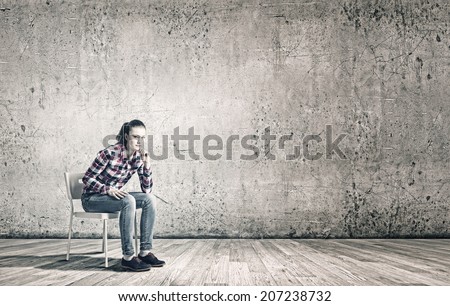 Young woman sitting on chair in empty room