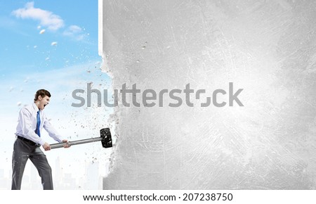 Young businessman breaking old wall with hammer