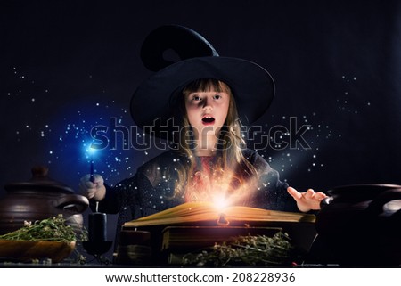 Little Halloween witch making magic with stick