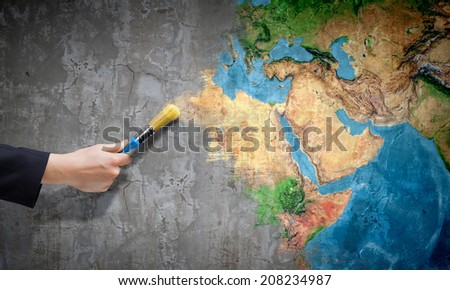 Close up of hand painting Earth planet with brush. Elements of this image are furnished by NASA