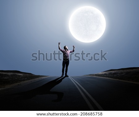 Young screaming man at night with big full moon at background