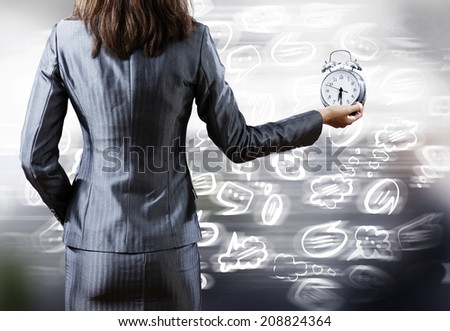 Rear view of businesswoman holding old alarm clock