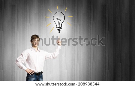 Schoolboy pointing at light bulb with finger. Idea concept