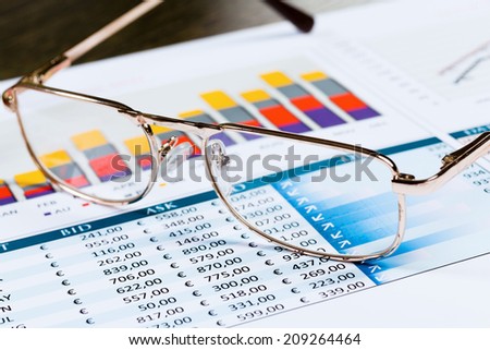 Eye glasses lying on papers with graphs and diagrams