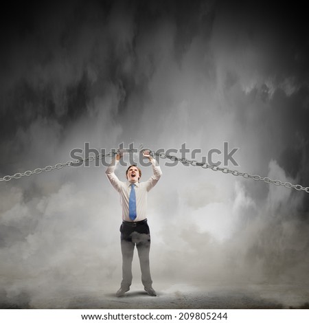 Young strong businessman tearing metal chain with hands